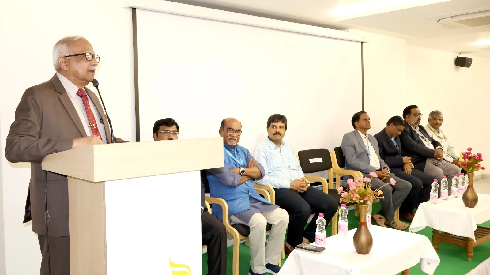 Dean Dr. H. Vinod Bhati delivering a speech with dignitaries seated on stage during Adhyay 2025