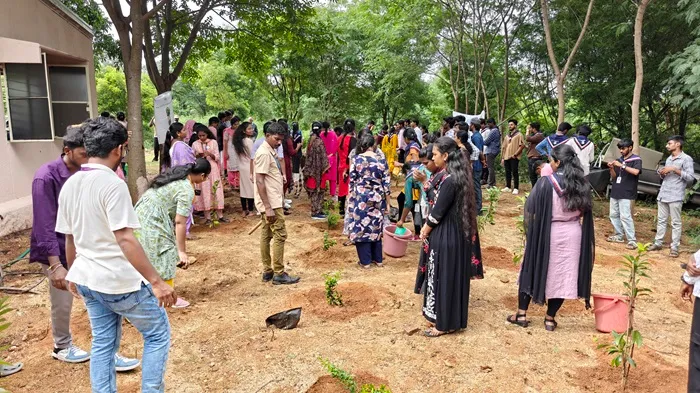 Group of volunteers posing by a young tree on campus