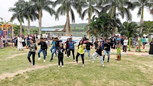 Flash-mob moment captured: students dance outdoors in front of peers and trees.