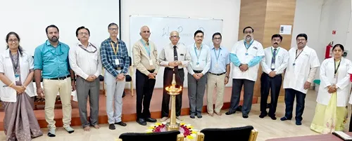 Group photo of university staff and guests standing behind a ceremonial lamp during an event